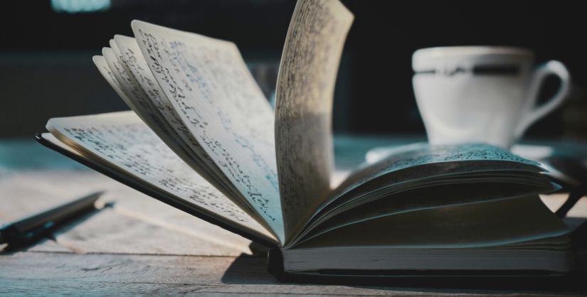 Journal on a desk with cup behind,