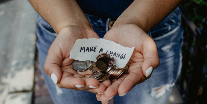 Woman's cupped hand with coins and a note that reads make a change